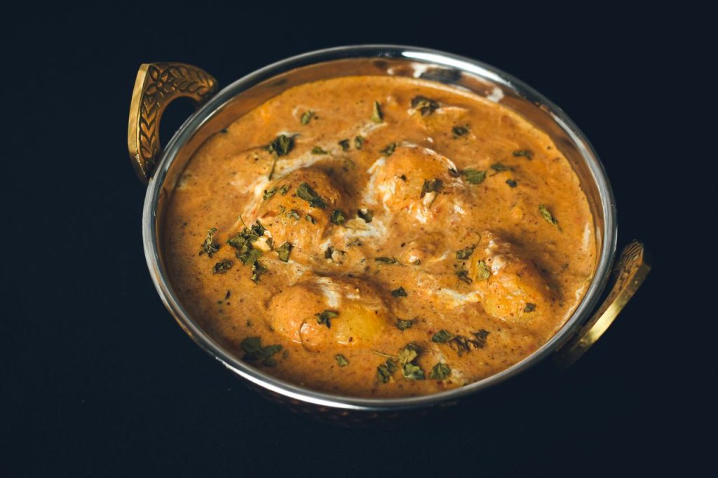 Delicious Dum Aloo curry served in a traditional Indian bowl, showcasing rich spices and fresh herbs.